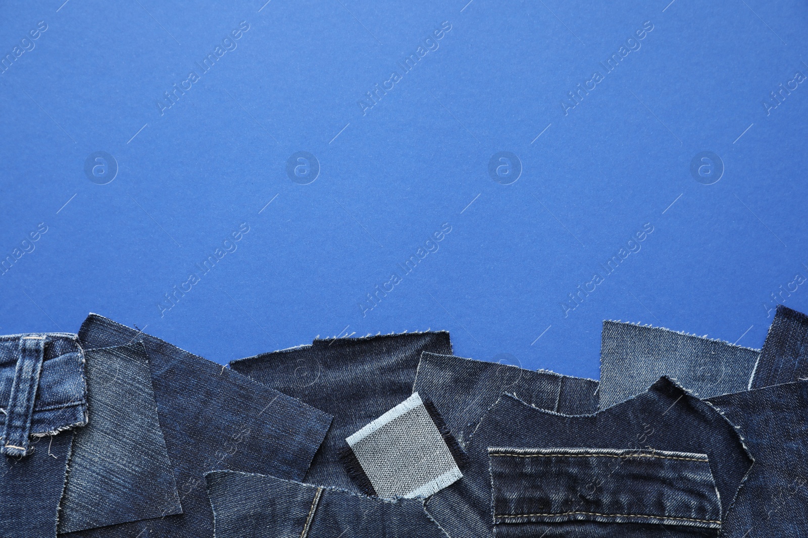 Photo of Flat lay composition with patches of old jeans on blue background. Space for text