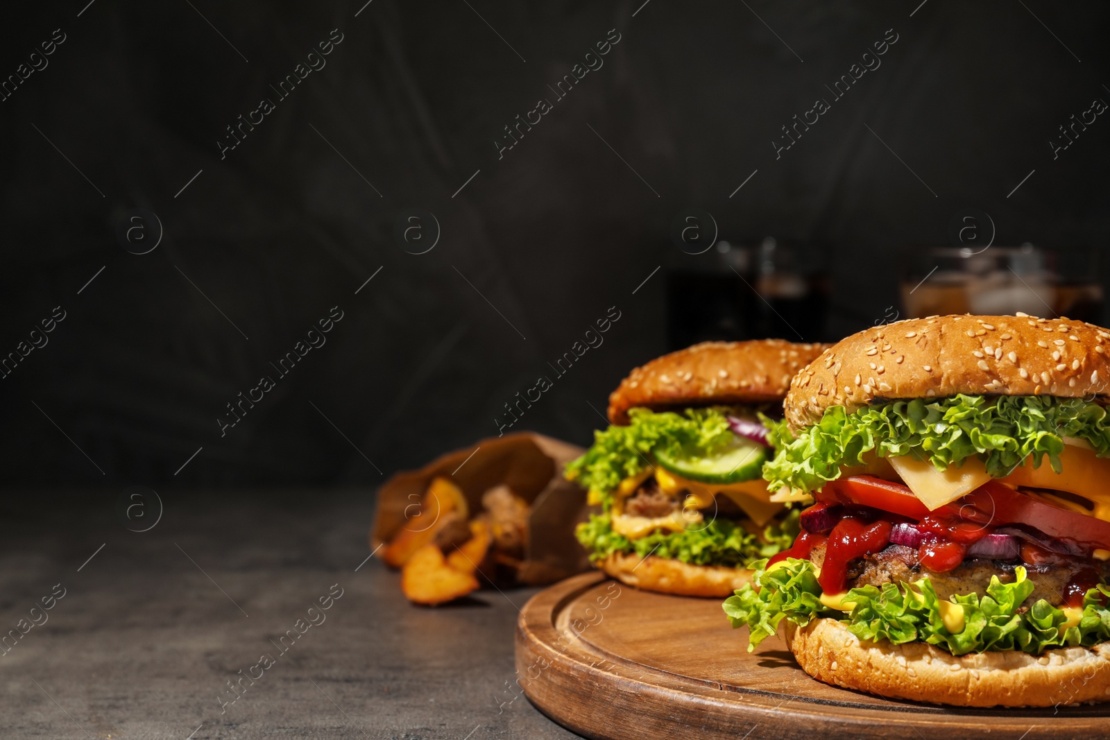 Photo of Tasty burgers and fried potatoes on table. Space for text