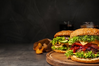 Photo of Tasty burgers and fried potatoes on table. Space for text