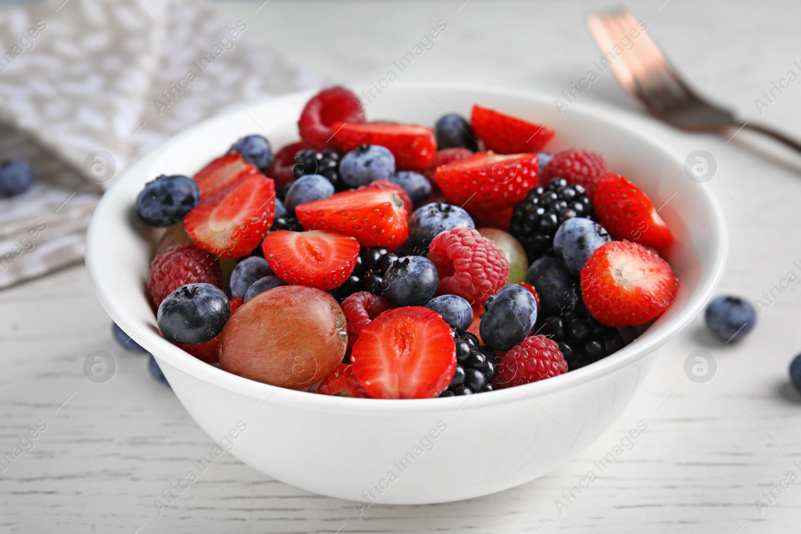 Photo of Fresh tasty fruit salad on white wooden table, closeup