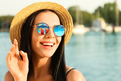 Image of Happy woman on vacation. Cocktails near swimming pool mirroring in her sunglasses