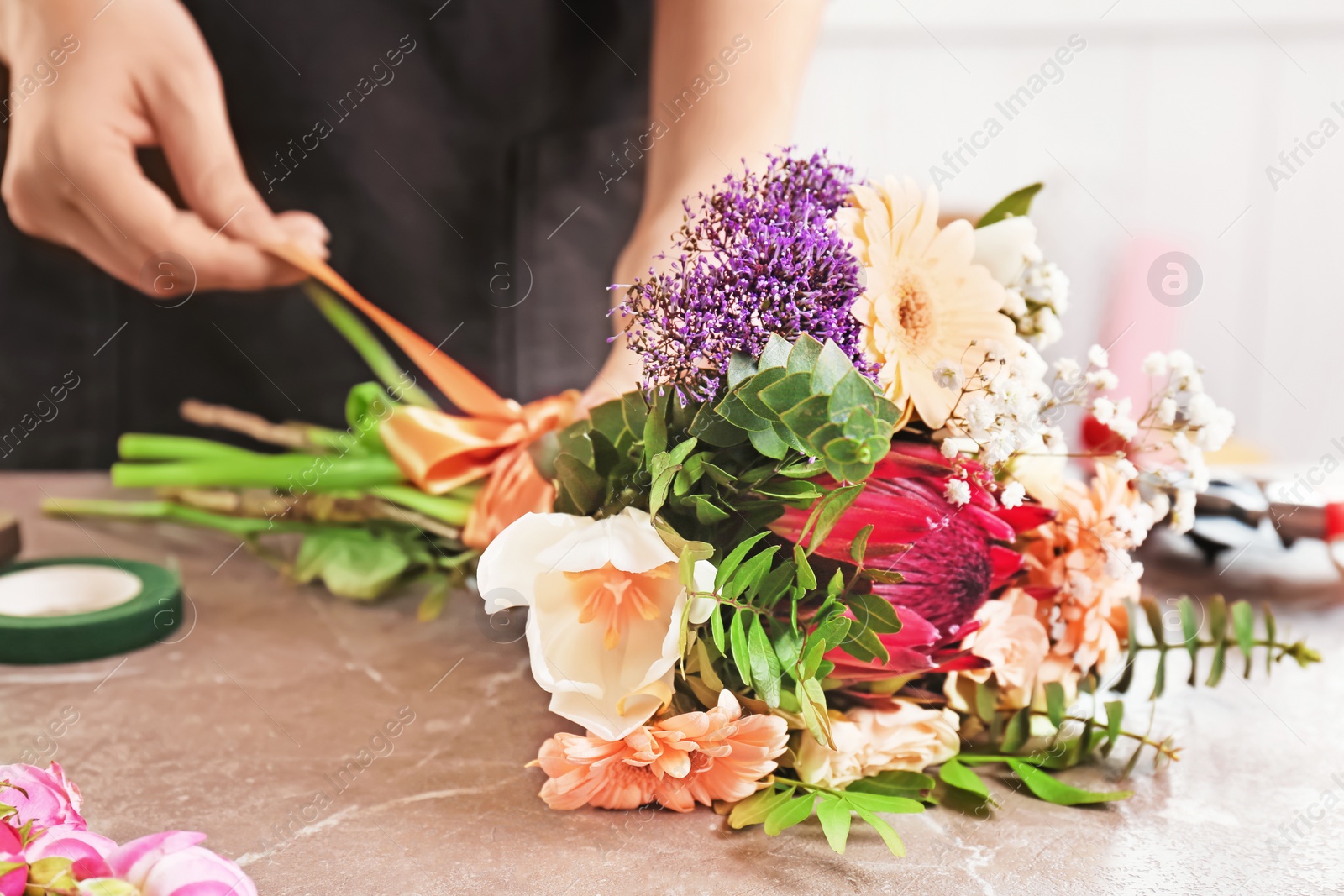 Photo of Female florist making beautiful bouquet at table