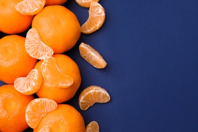 Photo of Fresh juicy tangerines on blue table, flat lay. Space for text