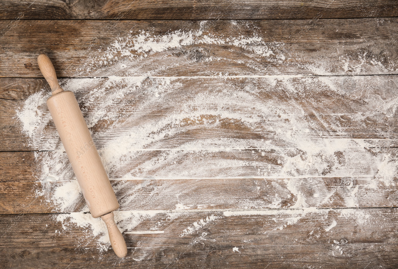 Photo of Flour and rolling pin on wooden table, flat lay