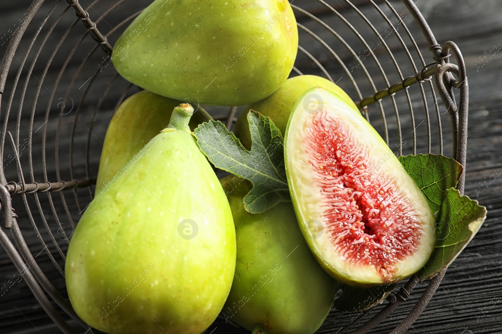 Photo of Fresh ripe figs in basket on wooden table, top view. Tropical fruit