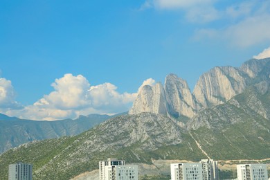 Photo of City near mountains under blue sky with clouds