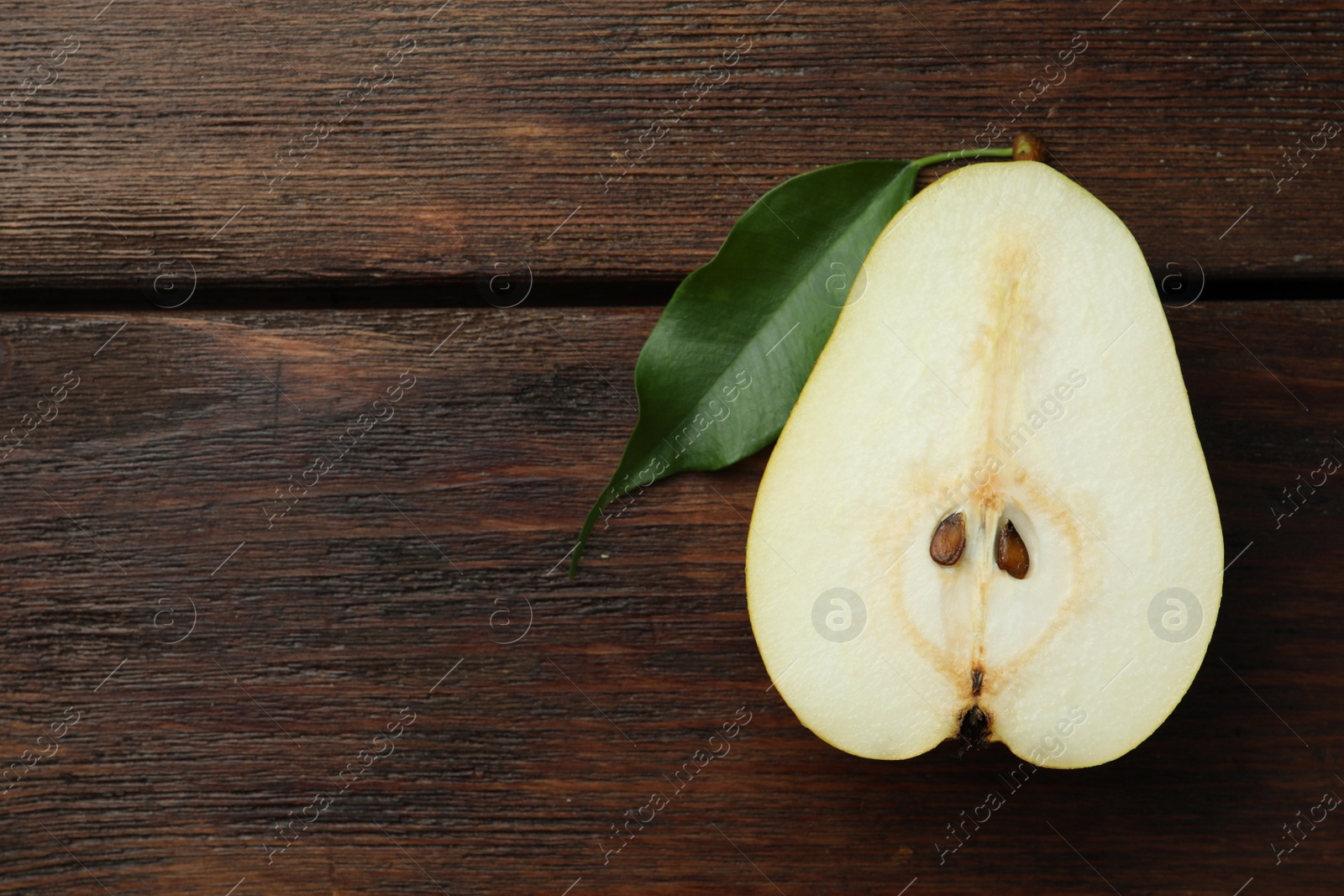 Photo of Half of tasty fresh pear on wooden table, top view. Space for text