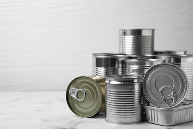Photo of Many closed tin cans on white marble table. Space for text