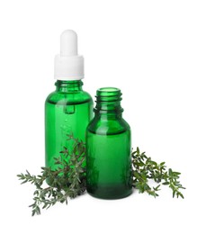 Bottles of thyme essential oil and fresh plant isolated on white
