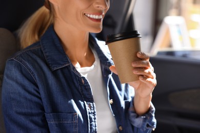 Photo of Coffee to go. Woman with paper cup of drink in car, closeup
