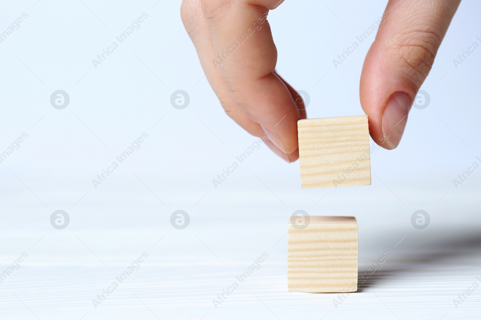 Photo of Woman arranging cubes on white background, closeup with space for text. Idea concept
