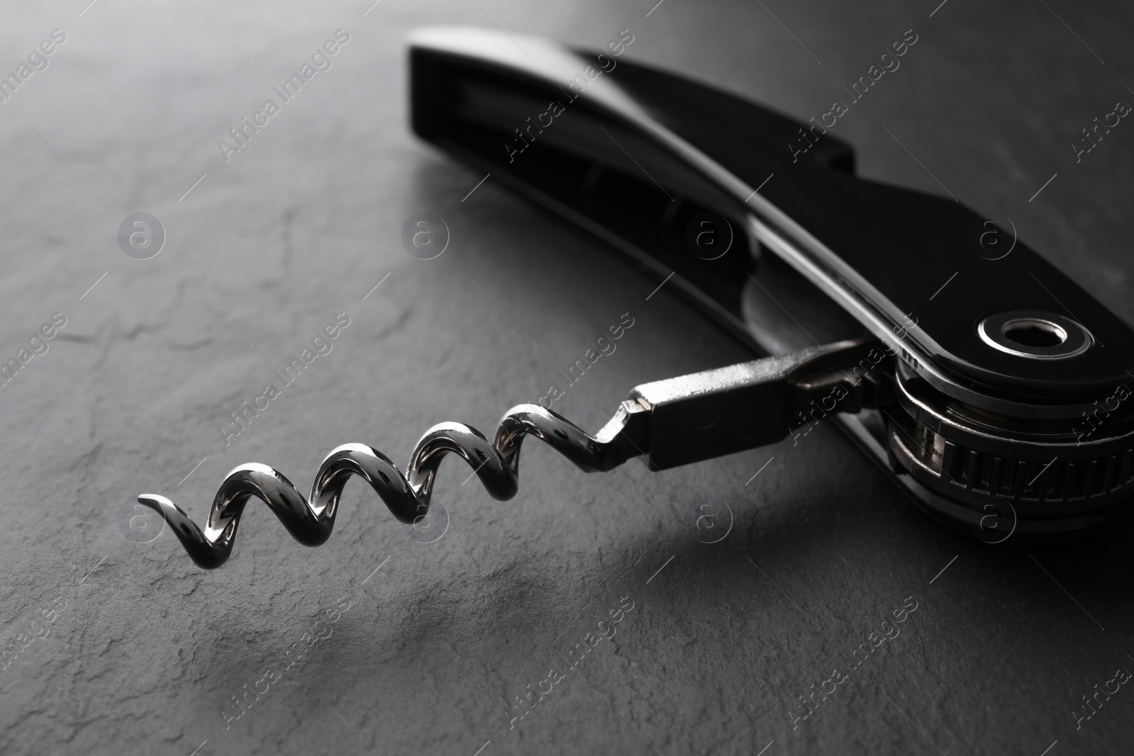 Photo of One corkscrew (sommelier knife) on grey textured table, closeup