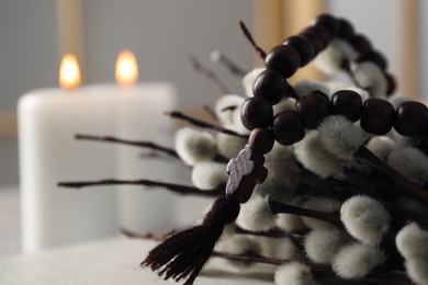 Rosary beads and willow branches on table, closeup. Space for text