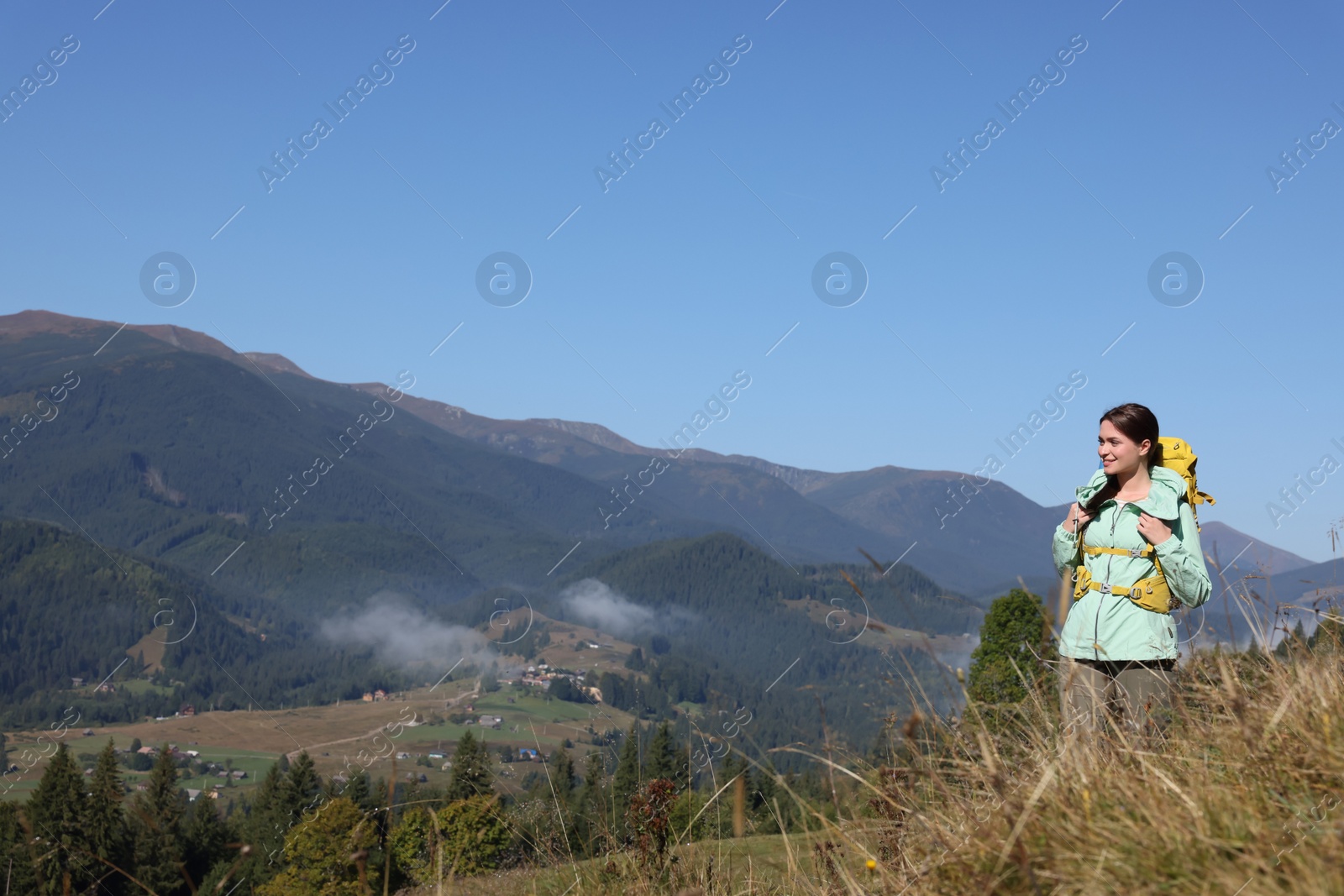 Photo of Tourist with backpack enjoying view in mountains on sunny day