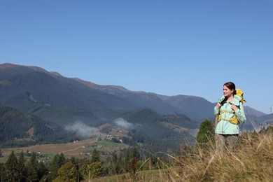 Tourist with backpack enjoying view in mountains on sunny day