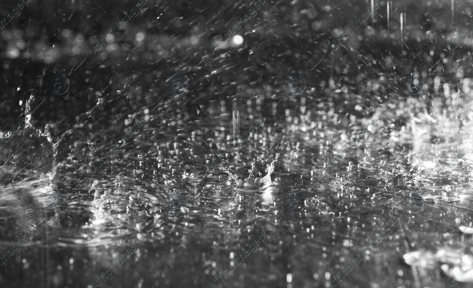 Photo of Heavy rain falling down on ground against dark background