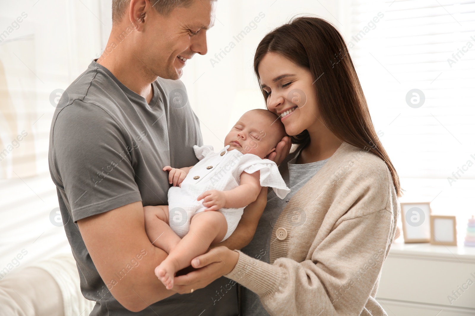 Photo of Happy couple holding their sleeping baby at home