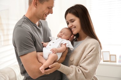 Photo of Happy couple holding their sleeping baby at home