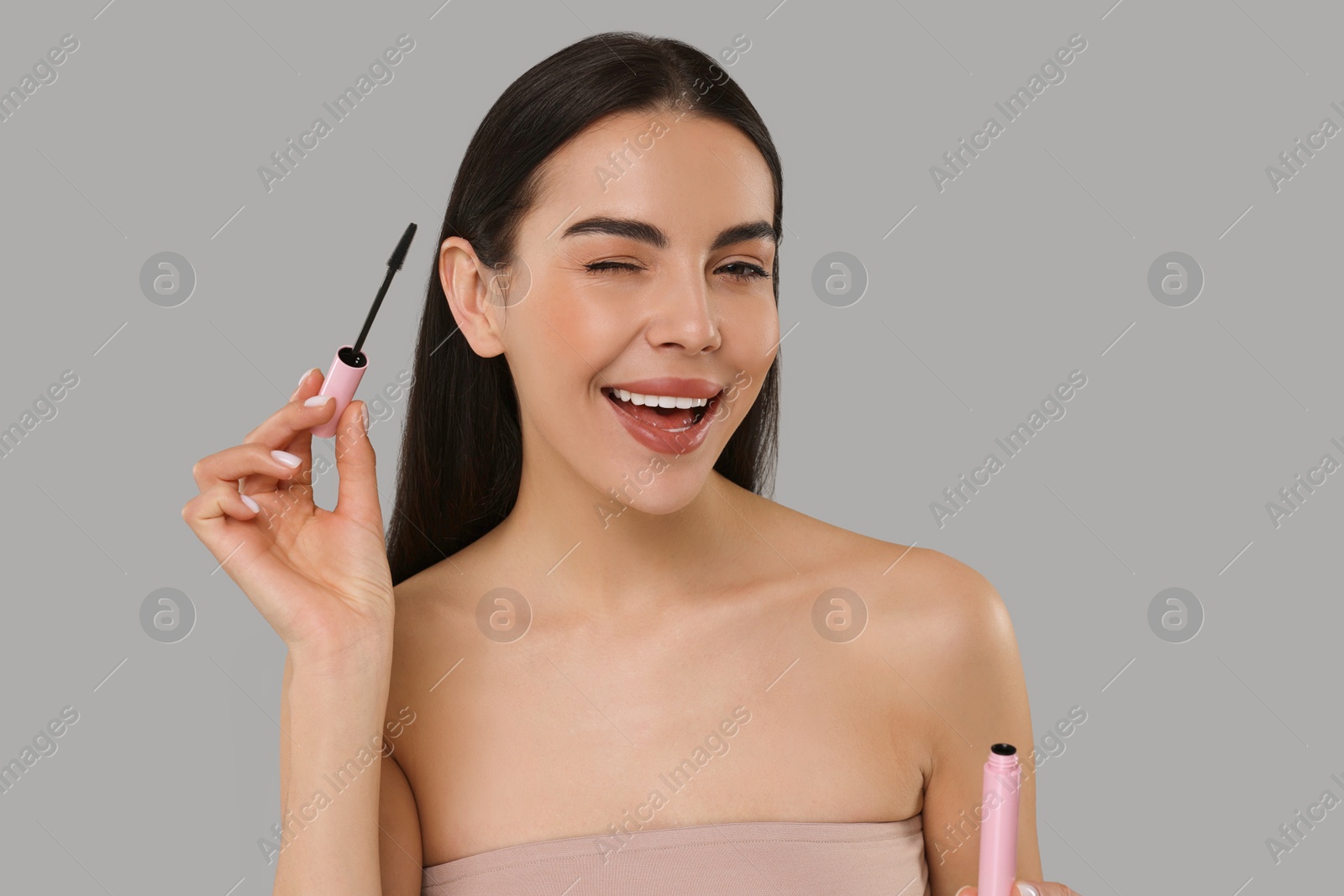 Photo of Beautiful young woman with mascara on grey background