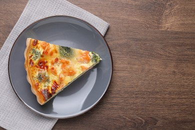 Piece of delicious homemade quiche with salmon and broccoli on wooden table, top view. Space for text