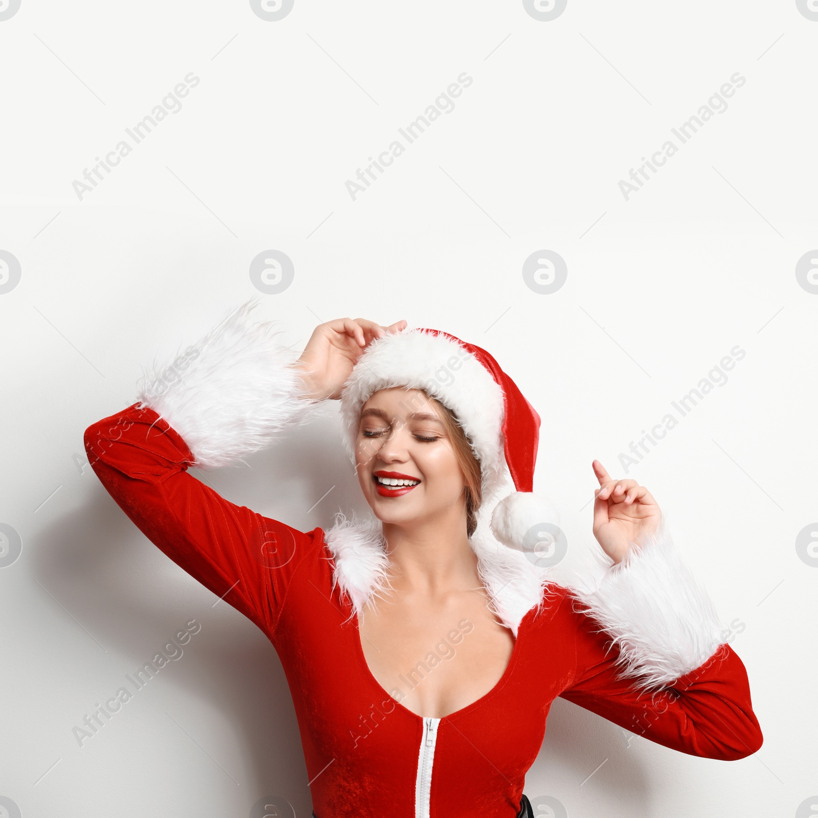 Photo of Beautiful Santa girl on light background. Christmas eve