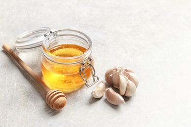 Photo of Jar with honey and garlic as cold remedies on table