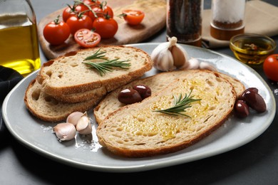 Photo of Tasty bruschettas with oil and rosemary on plate, closeup