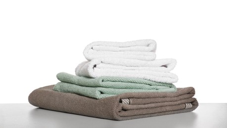 Photo of Soft colorful terry towels on light table against white background