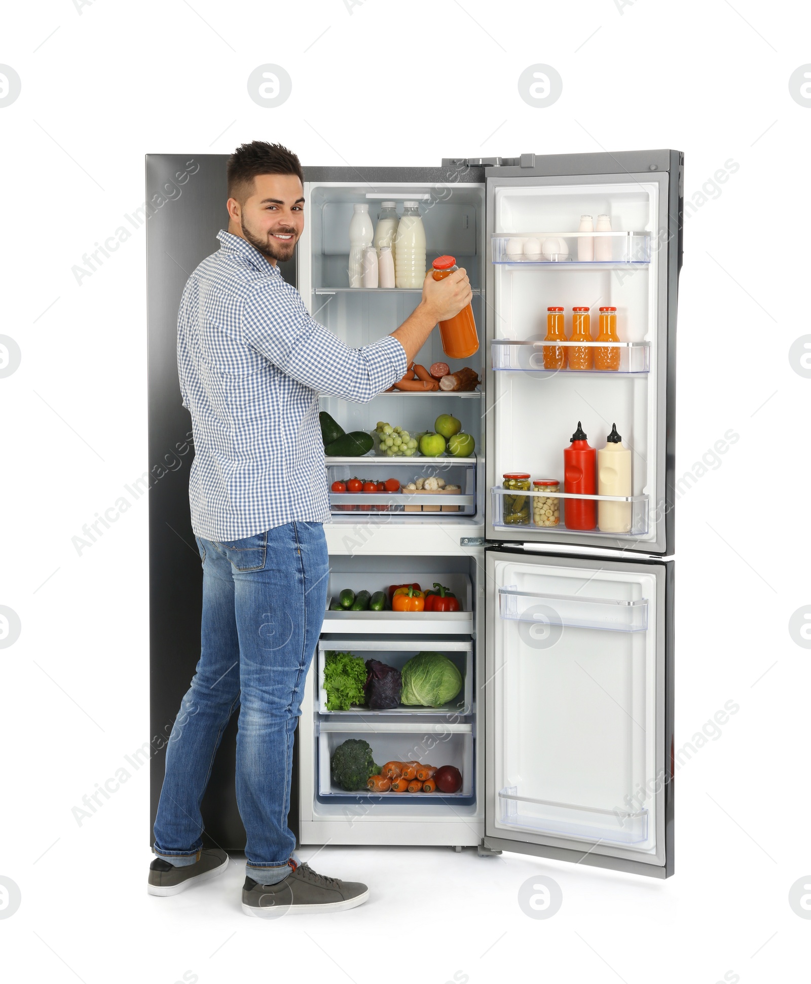 Photo of Young man taking juice out of refrigerator on white background