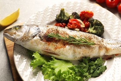 Delicious baked fish and vegetables on light grey table