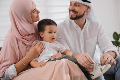 Happy Muslim family spending time together on sofa at home