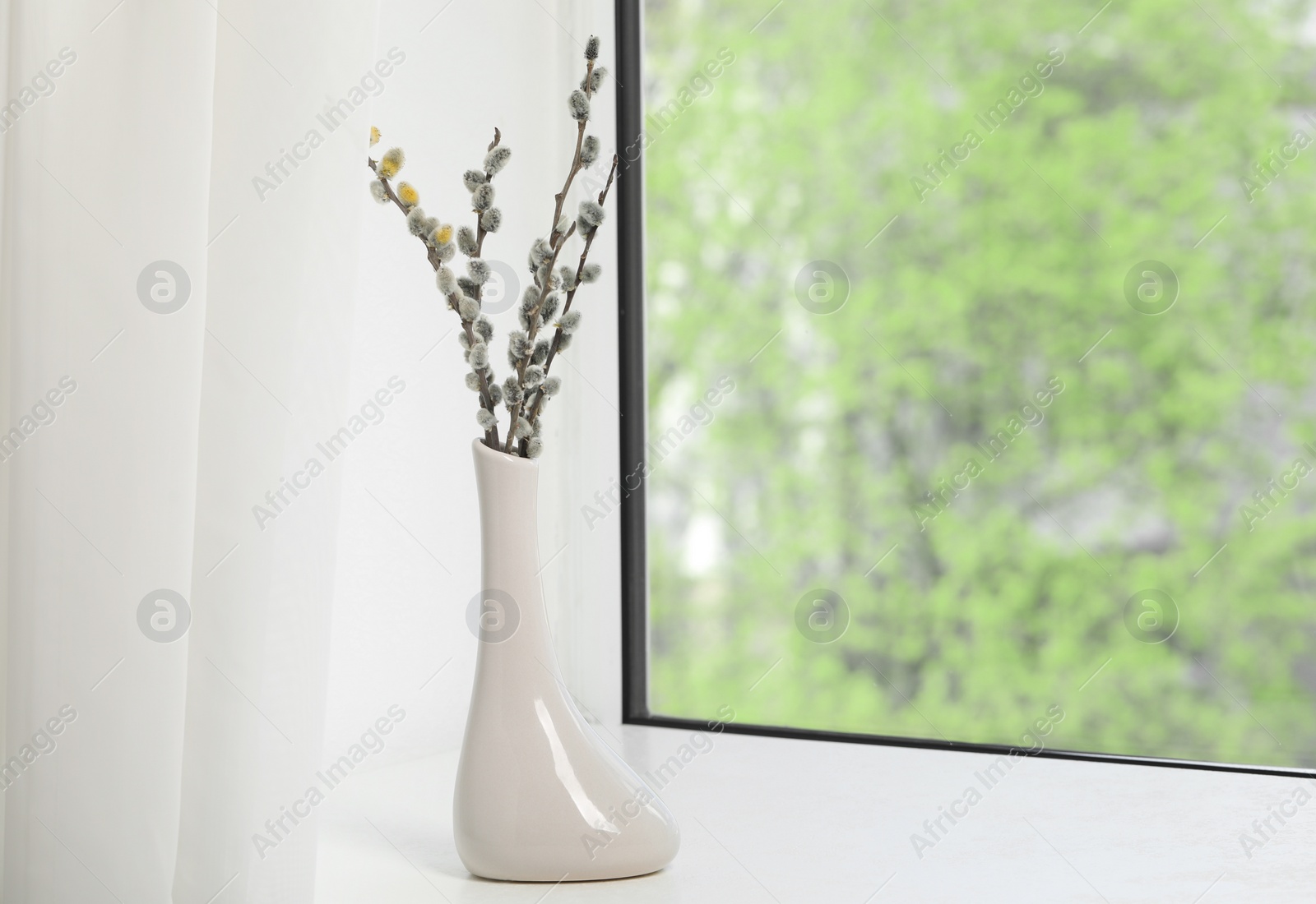 Photo of Beautiful pussy willow branches in vase on window sill indoors, space for text