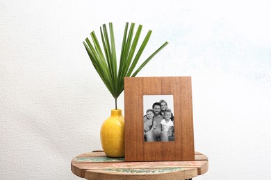 Black and white portrait of family in photo frame on table near white wall