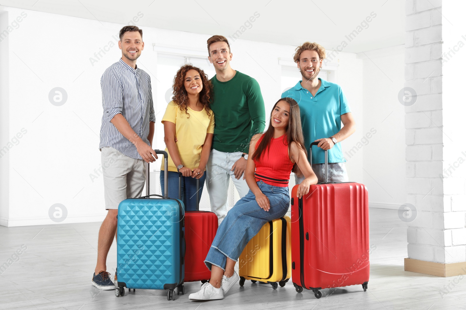 Photo of Group of young people with suitcases in light room