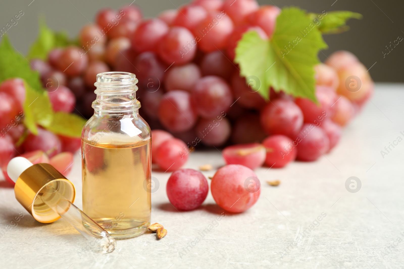 Photo of Natural grape seed oil and fresh berries on light table, space for text. Organic cosmetic