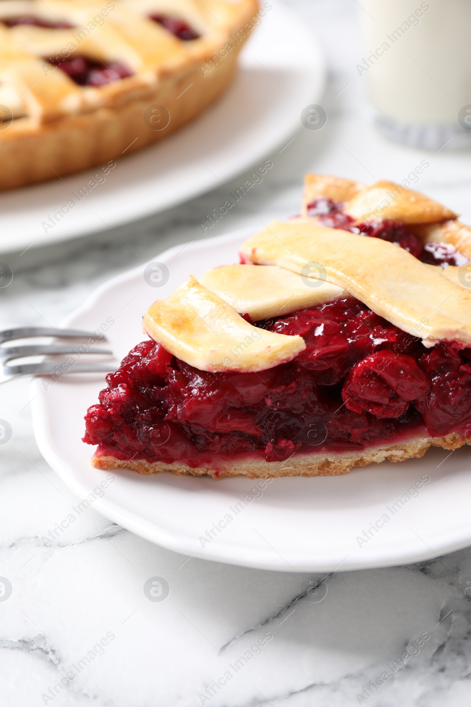 Photo of Slice of delicious fresh cherry pie on white marble table, closeup