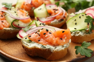 Photo of Tasty canapes with salmon served on light grey table, closeup