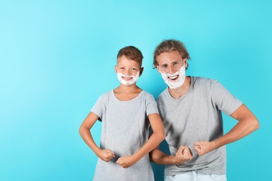 Photo of Father and son with shaving foam on faces against color background, space for text