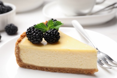 Photo of Piece of delicious cheesecake decorated with blackberries on table