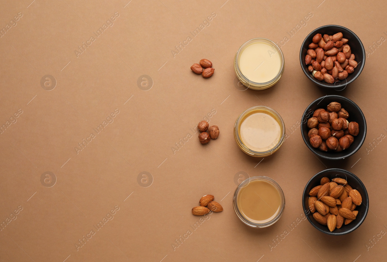 Photo of Different types of delicious nut butters and ingredients on brown background, flat lay. Space for text