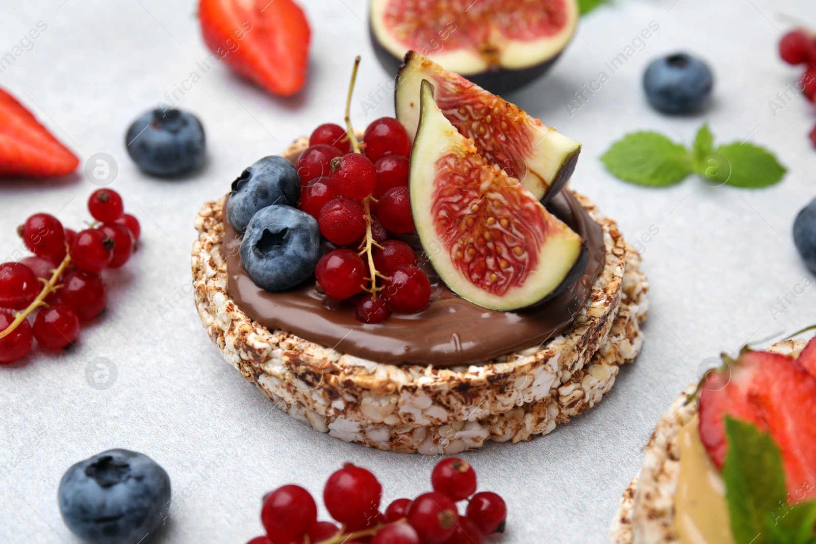 Photo of Tasty crispbreads with chocolate, figs and berries on light table, closeup