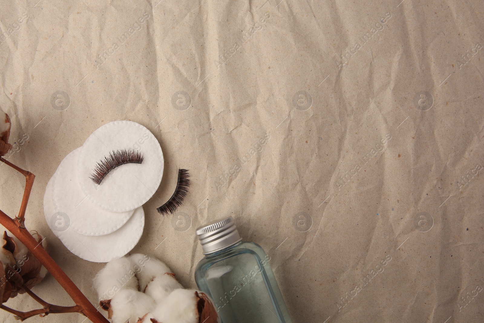 Photo of Flat lay composition with makeup remover and cotton flowers on crumpled paper, space for text