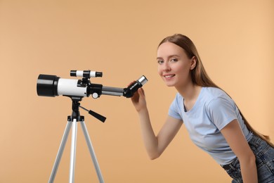 Happy astronomer with telescope on beige background