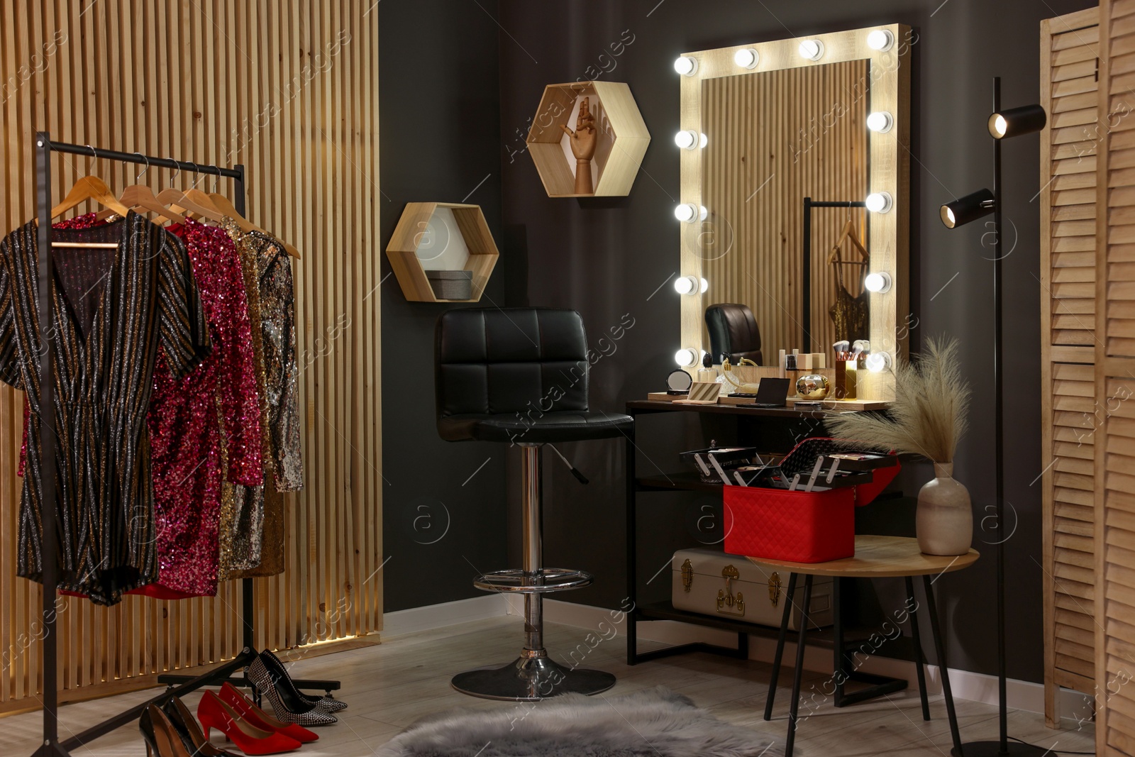 Photo of Makeup room. Stylish mirror near dressing table, chair and clothes rack indoors