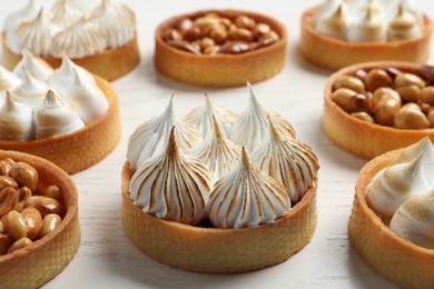 Photo of Many different tartlets on white wooden table, closeup. Delicious dessert