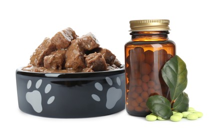 Image of Wet pet food in feeding bowl and bottle with vitamin pills on white background