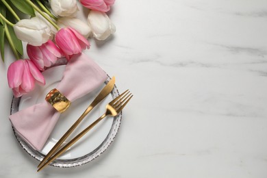 Photo of Stylish table setting with cutlery and tulips on white marble background, flat lay. Space for text