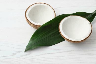 Composition with halves of coconut on white wooden background