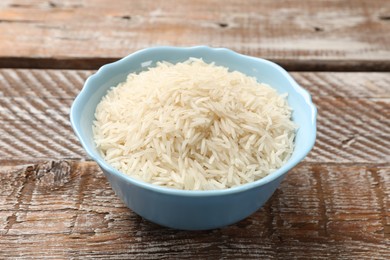 Photo of Raw basmati rice in bowl on wooden table