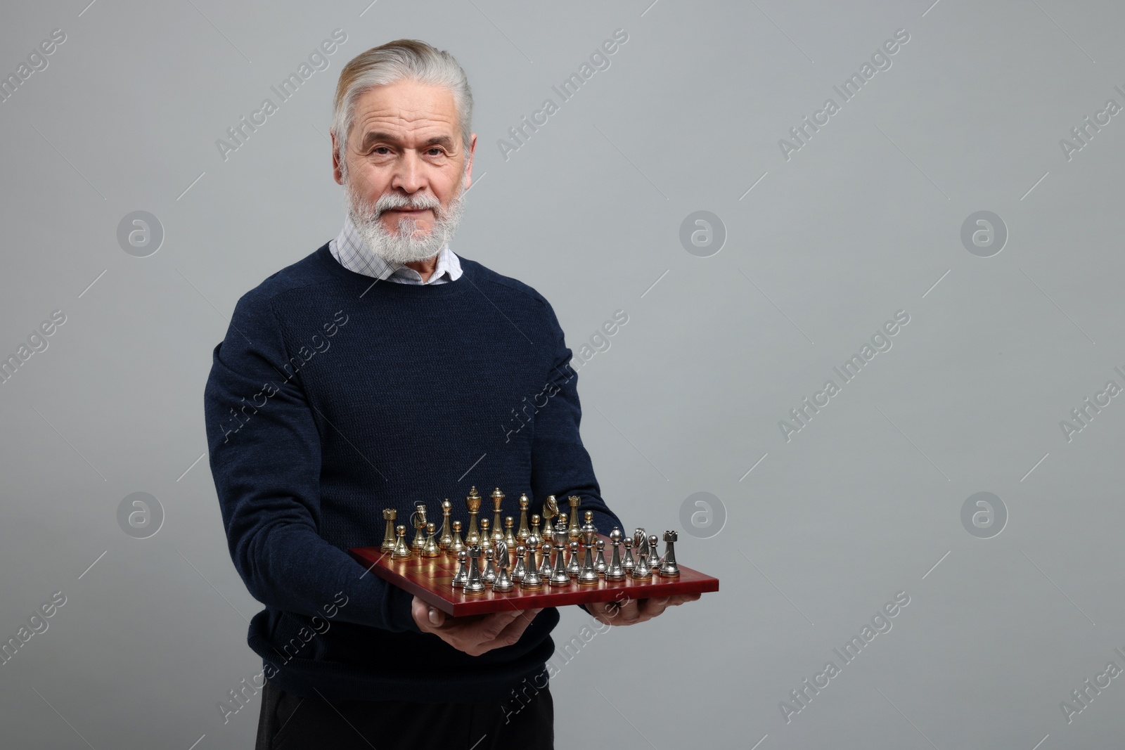 Photo of Man with chessboard and game pieces on light gray background, space for text